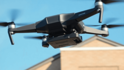 A drone hovers above a commercial building's roof under a clear blue sky, symbolizing innovation in infrastructure management and advanced roof ins...